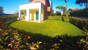 A modern two-story house with a covered patio area and a well-maintained lawn. - Residence Le Piramidi (Caorle)
