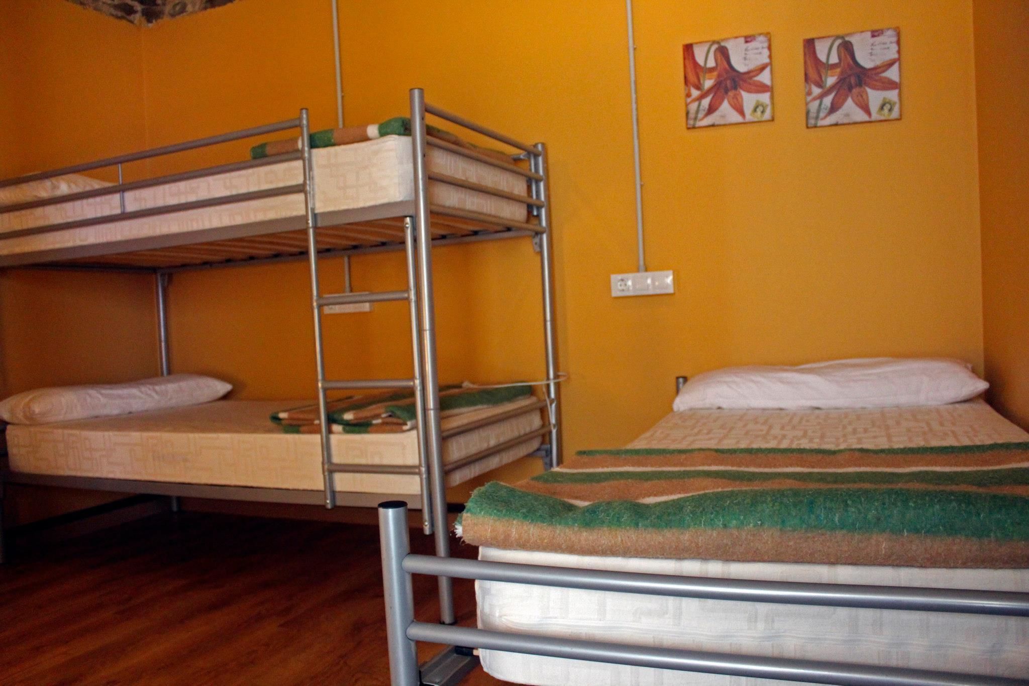 Dormitorio con literas, suelo de madera y pared amarilla.