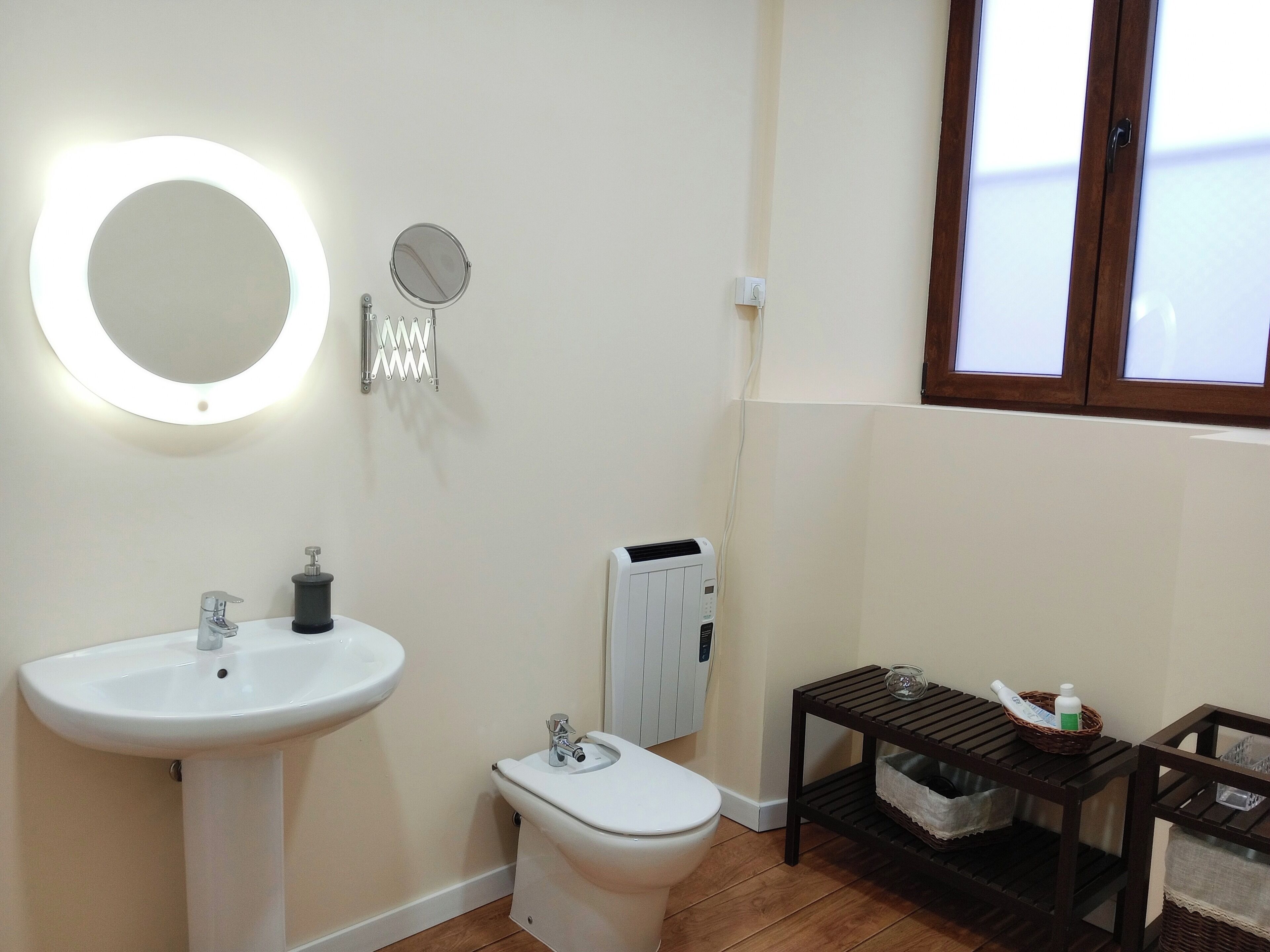 Een badkamer met een wastafel op een voetstuk, een toilet, een spiegel en een radiator.