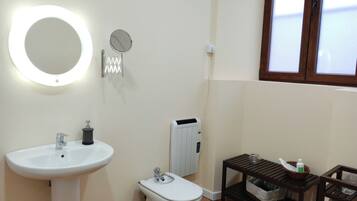 Een badkamer met een wastafel op een voetstuk, een toilet, een spiegel en een radiator.