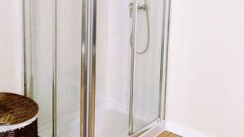 Un receveur de douche d’angle avec des portes en verre transparent et un cadre en chrome.