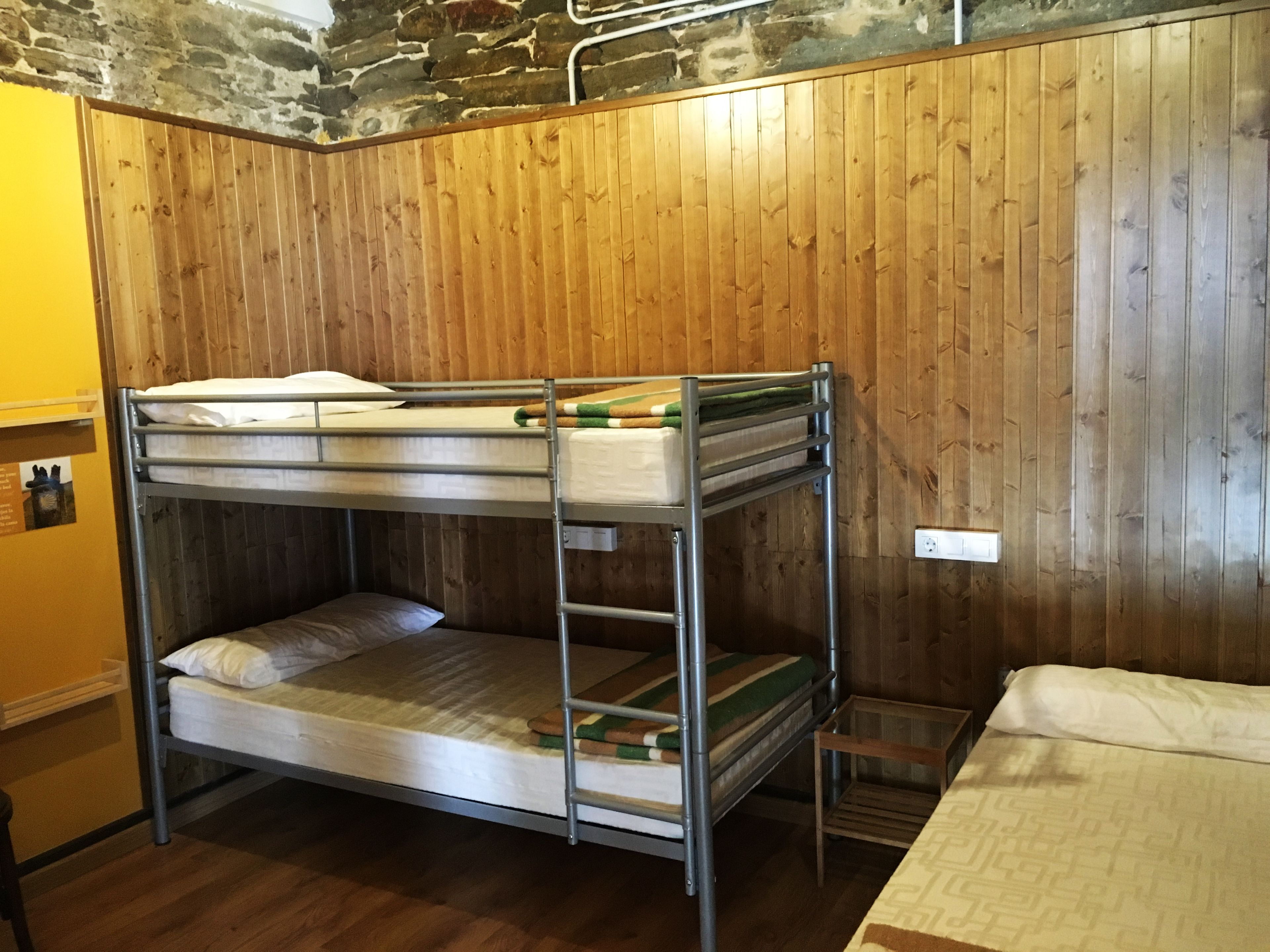 Dormitorio con literas, paredes de madera y techo de piedra.