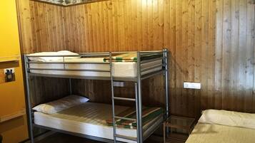 Dormitorio con literas, paredes de madera y techo de piedra.