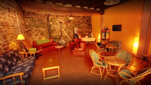 Un salón acogedor con pared de piedra, sofás de cuero, sillas de mimbre y una mesita.