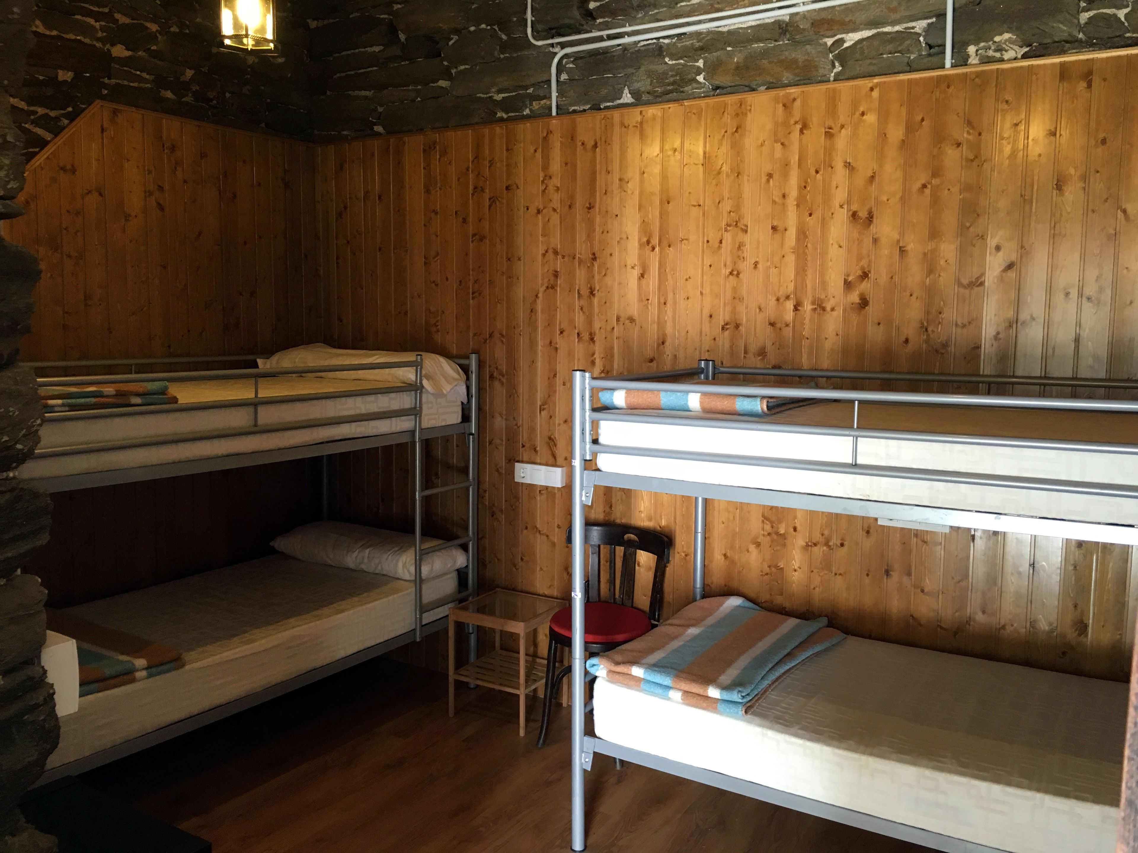 Habitación con literas, paredes de madera y una pared de acento de piedra.