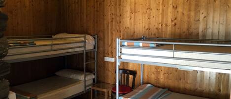 A bunk bed room with wooden walls and a stone accent wall.