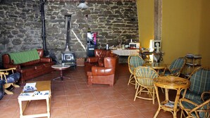 Una sala de estar acogedora con pared de piedra, sofás de cuero, sillones de mimbre y chimenea.