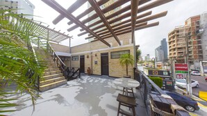 A rooftop patio with a pergola, a palm tree, and a view of the cityscape. - Economy Flat (Natal)