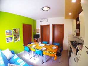 A compact living space with a dining area, kitchenette, and a sofa. - Appartamenti Levante (Caorle)