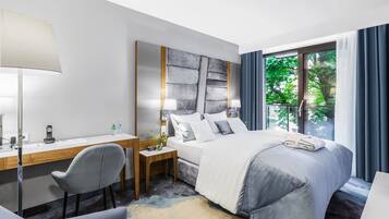 A modern hotel room with a bed, desk, chair, and a large window with curtains.