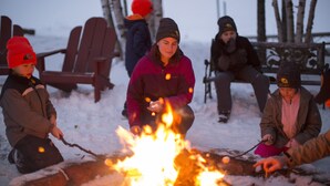 A group of people around a campfire in a snowy outdoor setting. - Skyport Lodge (Grand Marais)
