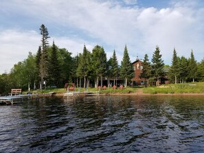 A lakeside cabin with a dock, surrounded by tall trees and a clear sky. - Skyport Lodge (Grand Marais)