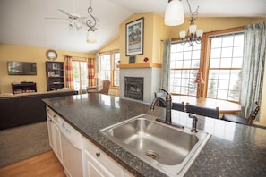 A kitchen with a granite countertop, stainless steel sink, and a fireplace. - Skyport Lodge (Grand Marais)