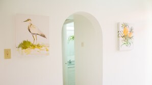 Ein Flur mit zwei Kunstwerken an den Wänden, eines zeigt einen Vogel, das andere tropische Blumen.