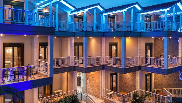 A multi-story hotel with balconies and outdoor seating areas. - Paradise (Volvi)