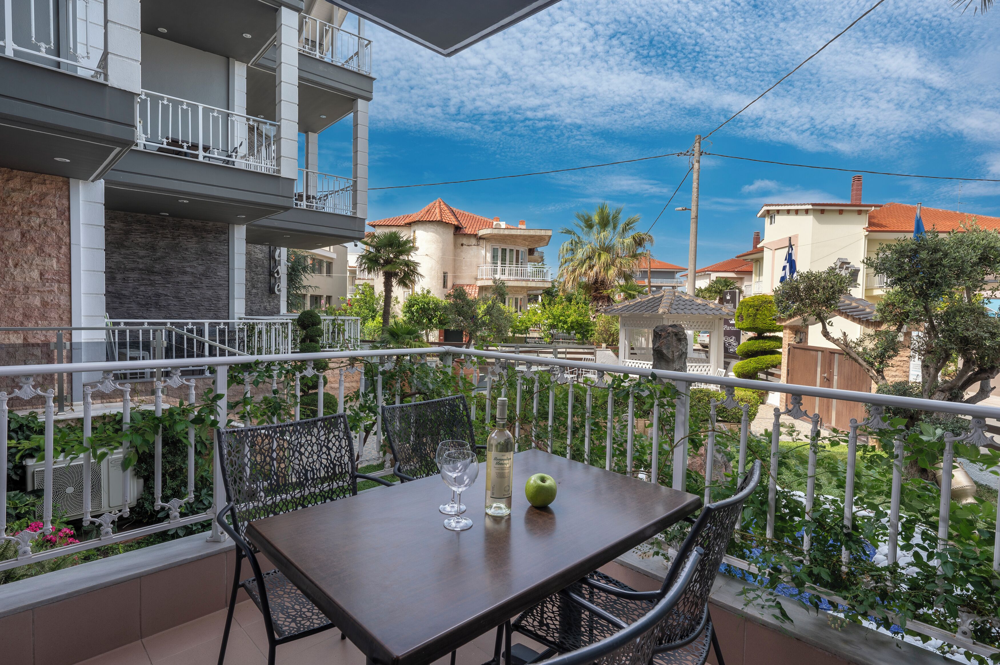 A balcony with a table, chairs, a bottle, and an apple.