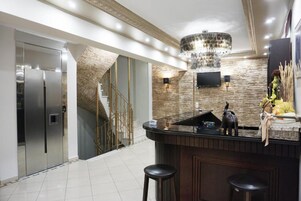 Una cocina moderna con una isla central, electrodomésticos de acero inoxidable, una araña y un elemento decorativo en la pared.
