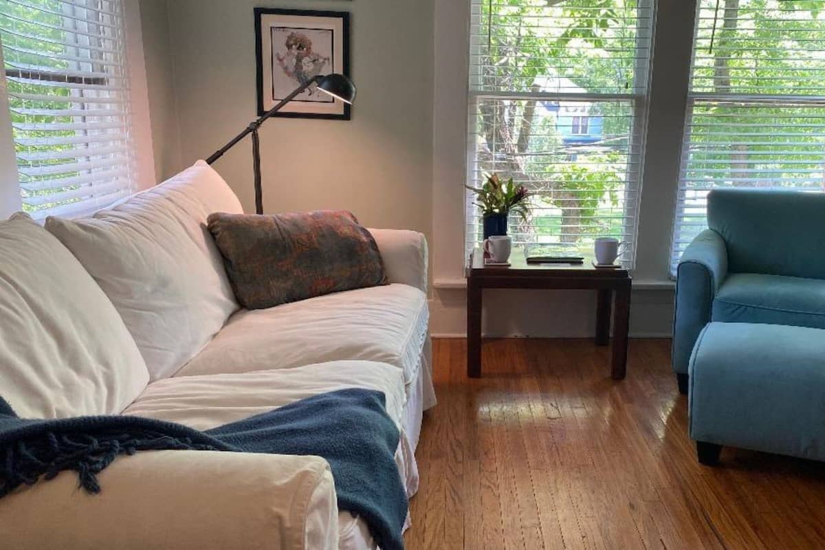 A living room with a white sofa, a blue armchair, a wooden coffee table, and a floor lamp.