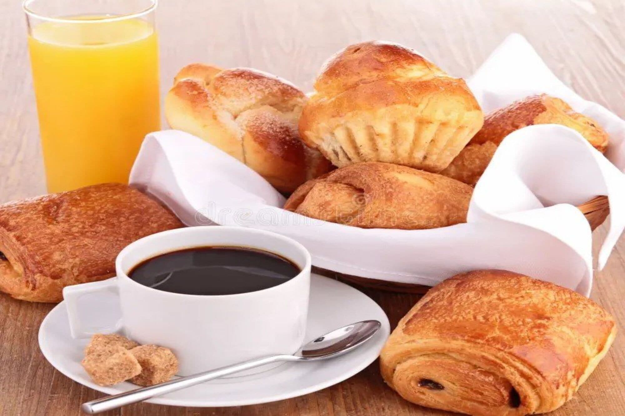 A breakfast setting with pastries, a glass of orange juice, and a cup of coffee.