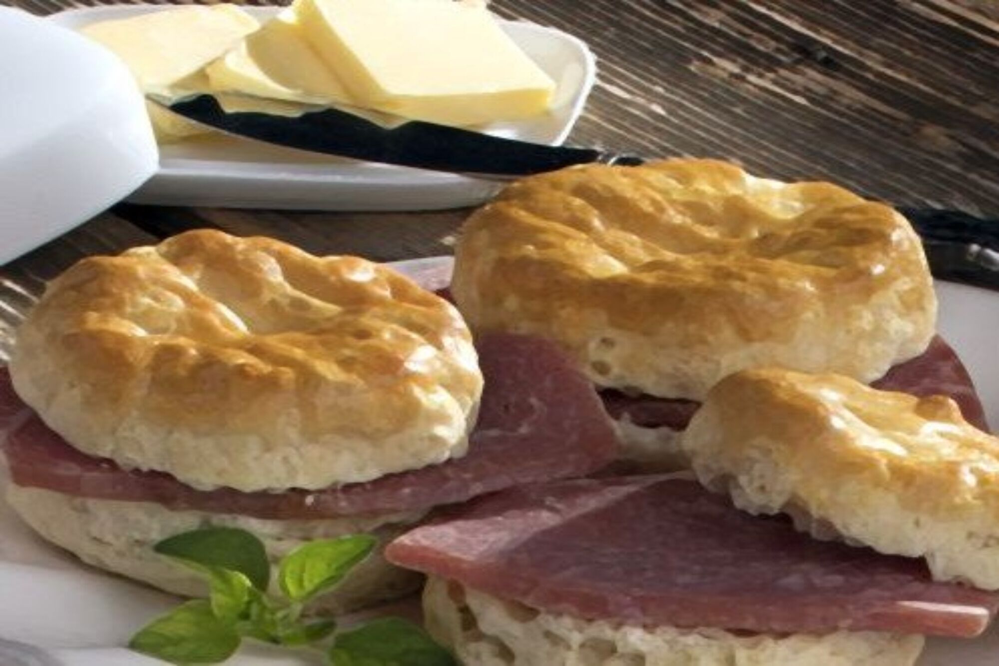 Three biscuits with ham and cheese, and a plate of butter.