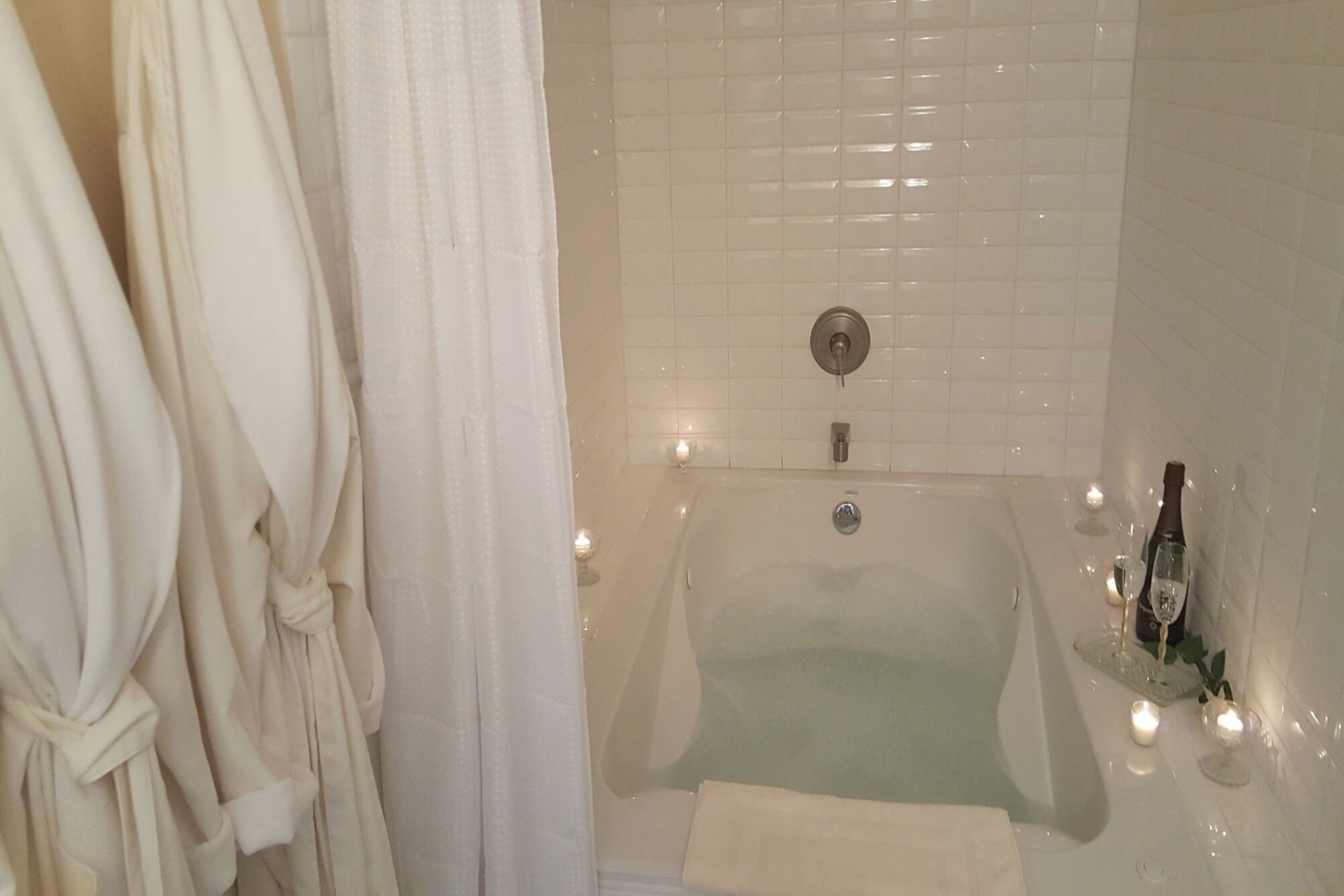 Un bagno con una vasca, un asciugamano e delle candele.
