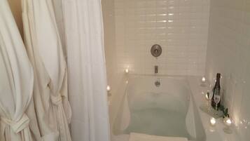 Un bagno con una vasca, un asciugamano e delle candele.