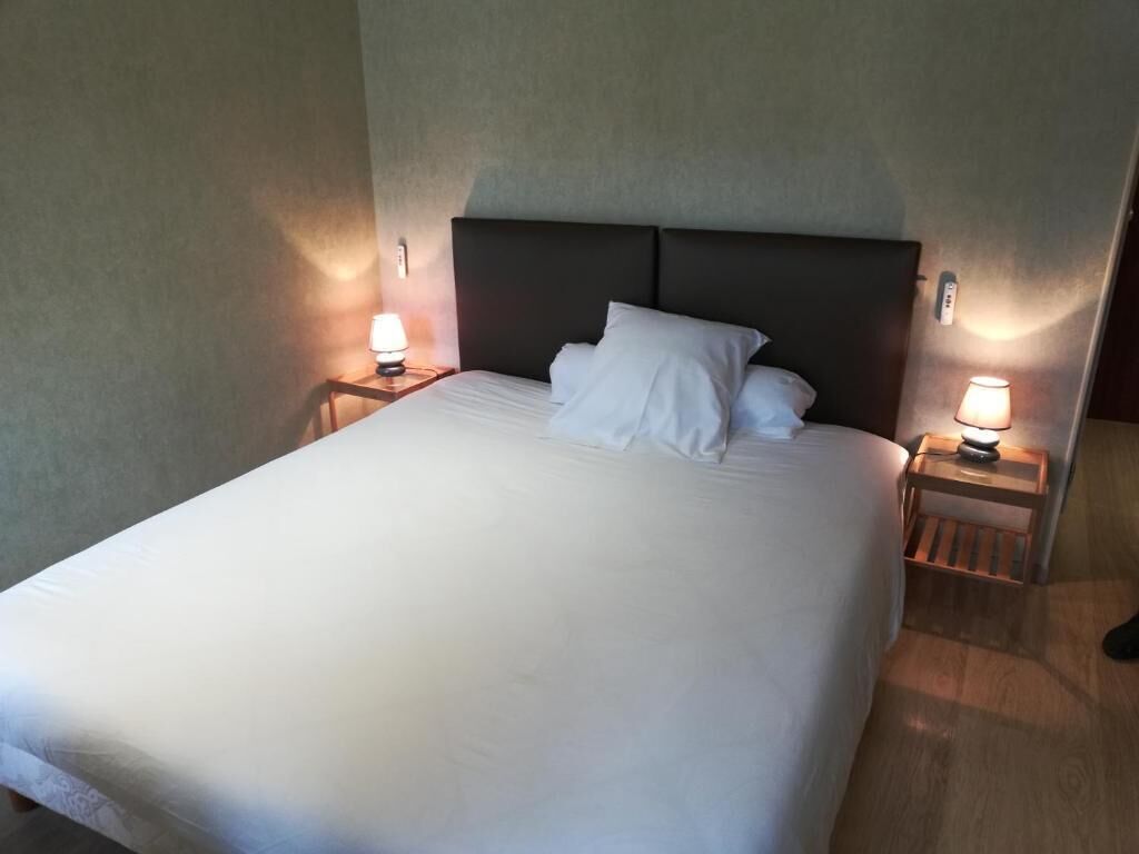 Een hotelkamer met een groot bed, twee nachtkastjes met lampen en een hoofdbord.
