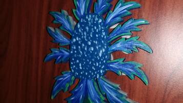 Una flor de papel azul y verde con motas blancas sobre una superficie de madera.