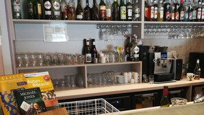 A bar area with shelves of liquor bottles, glasses, and a coffee machine.