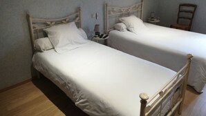 Two single beds with wooden frames, white bedding, and bedside tables with lamps.