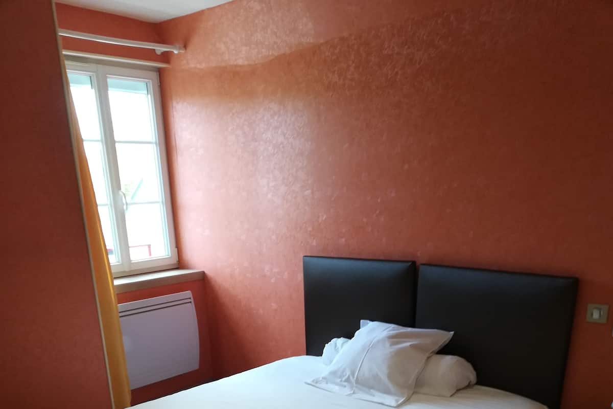 A bedroom with a bed, a window, and a radiator.