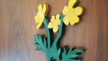Una superficie de madera con un corte decorativo de una planta verde con flores amarillas.