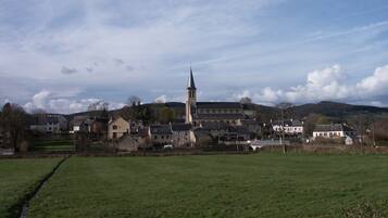 Ländliche Landschaft mit einer markanten Kirche, deren hoher Turm dominiert, umgeben von Wohnhäusern und offenen Feldern.