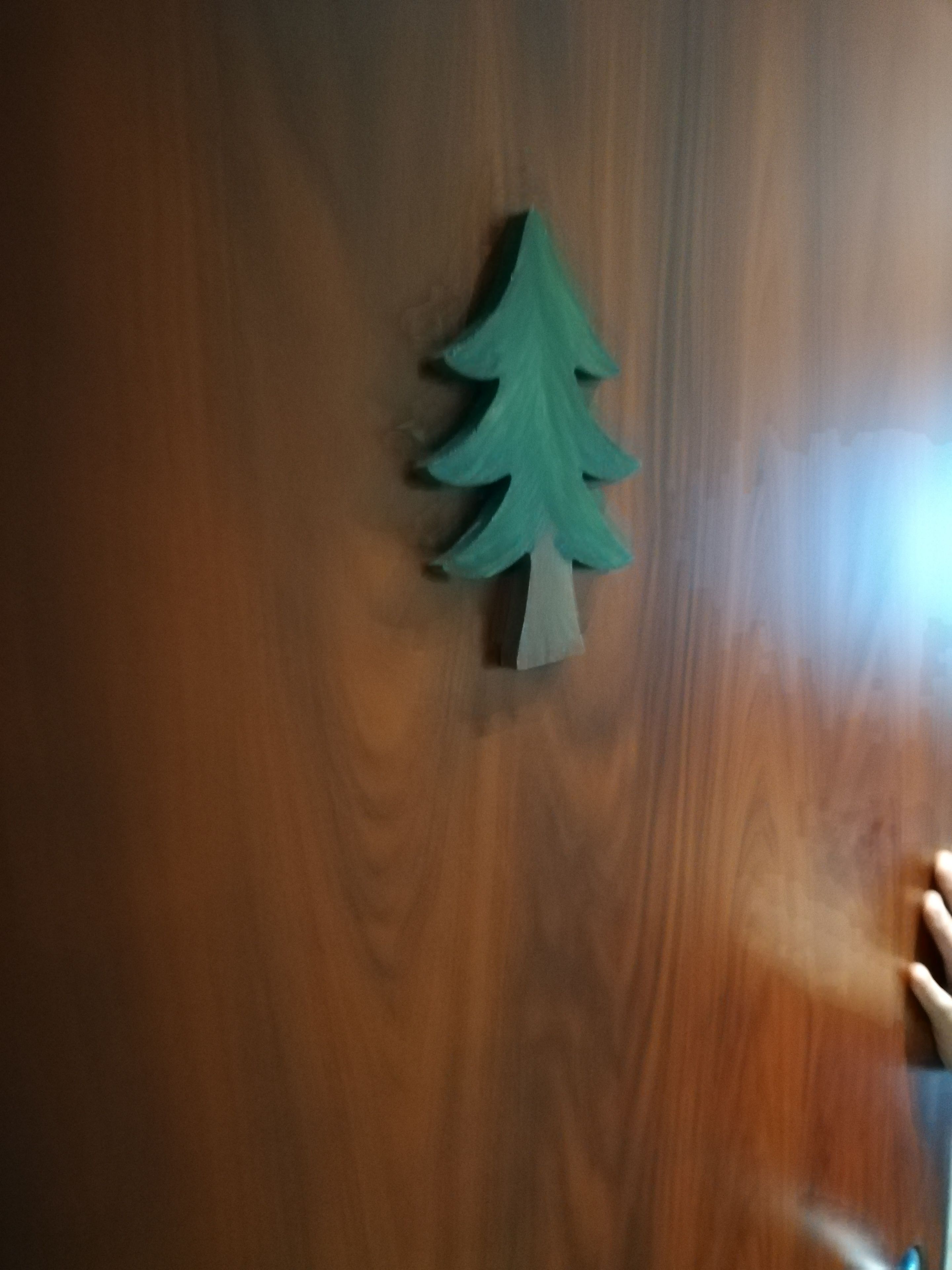 Una puerta de madera con un recorte de árbol de Navidad en papel verde.