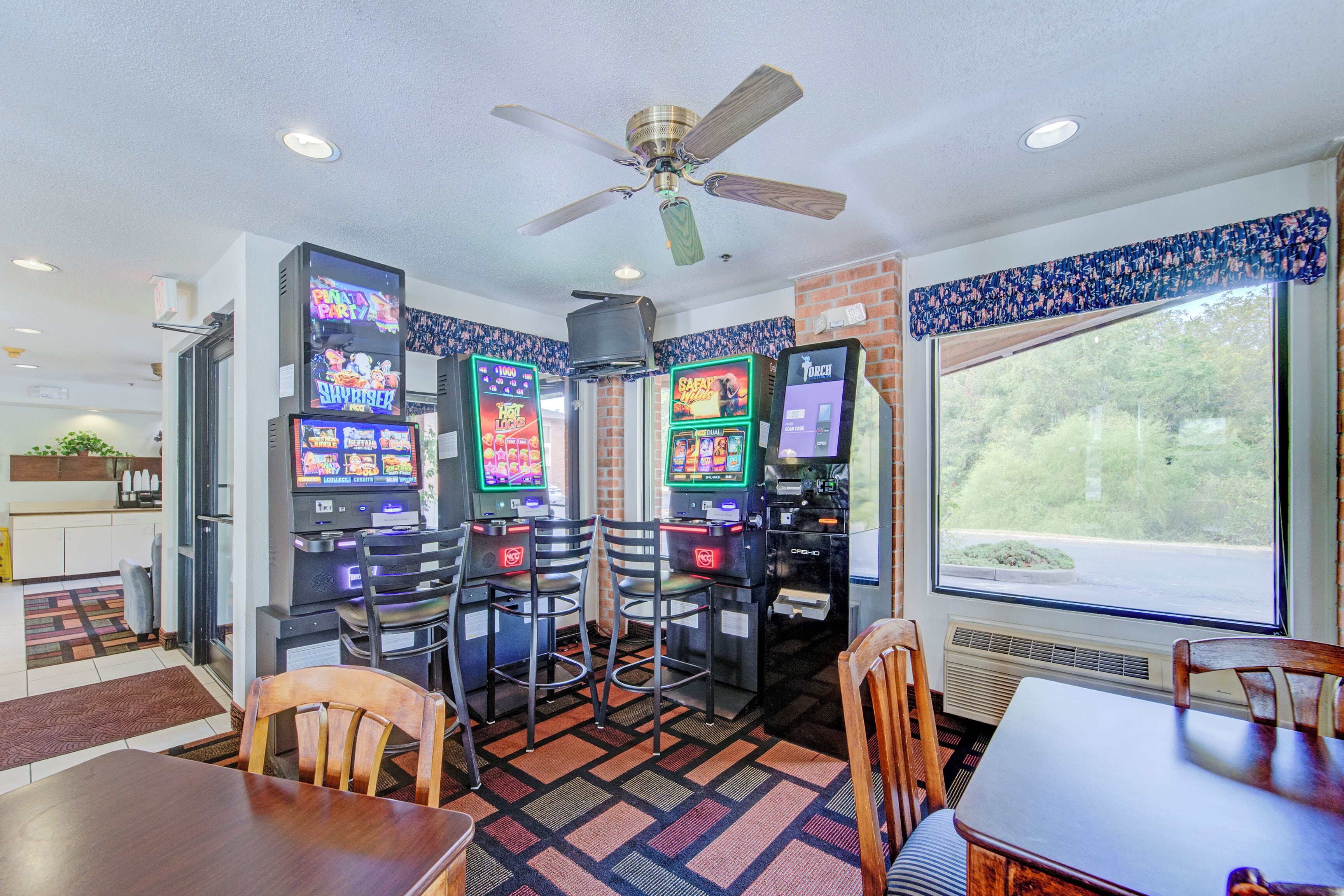 A room with a ceiling fan, a window with a view, and a wall-mounted air conditioning unit.