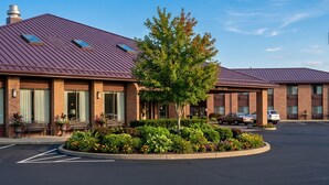 A hotel with a brick facade, multiple windows, and a parking lot. - Capital O Amerihost Inn and Suites Fulton Hwy 54 MO (Fulton)