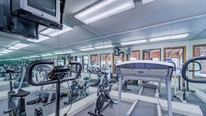 A gym with various exercise equipment, including treadmills, stationary bikes, and weight machines. - Capital O Amerihost Inn and Suites Fulton Hwy 54 MO (Fulton)