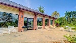 A building with a brick facade, large windows, and outdoor seating with chairs and a table. - Capital O Amerihost Inn and Suites Fulton Hwy 54 MO (Fulton)