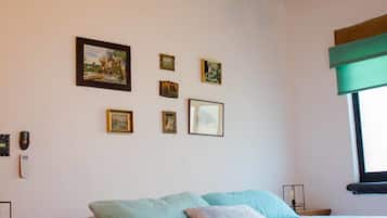 Un dormitorio con una cama, vigas de madera en el techo, un ventilador de techo y cuadros en la pared.