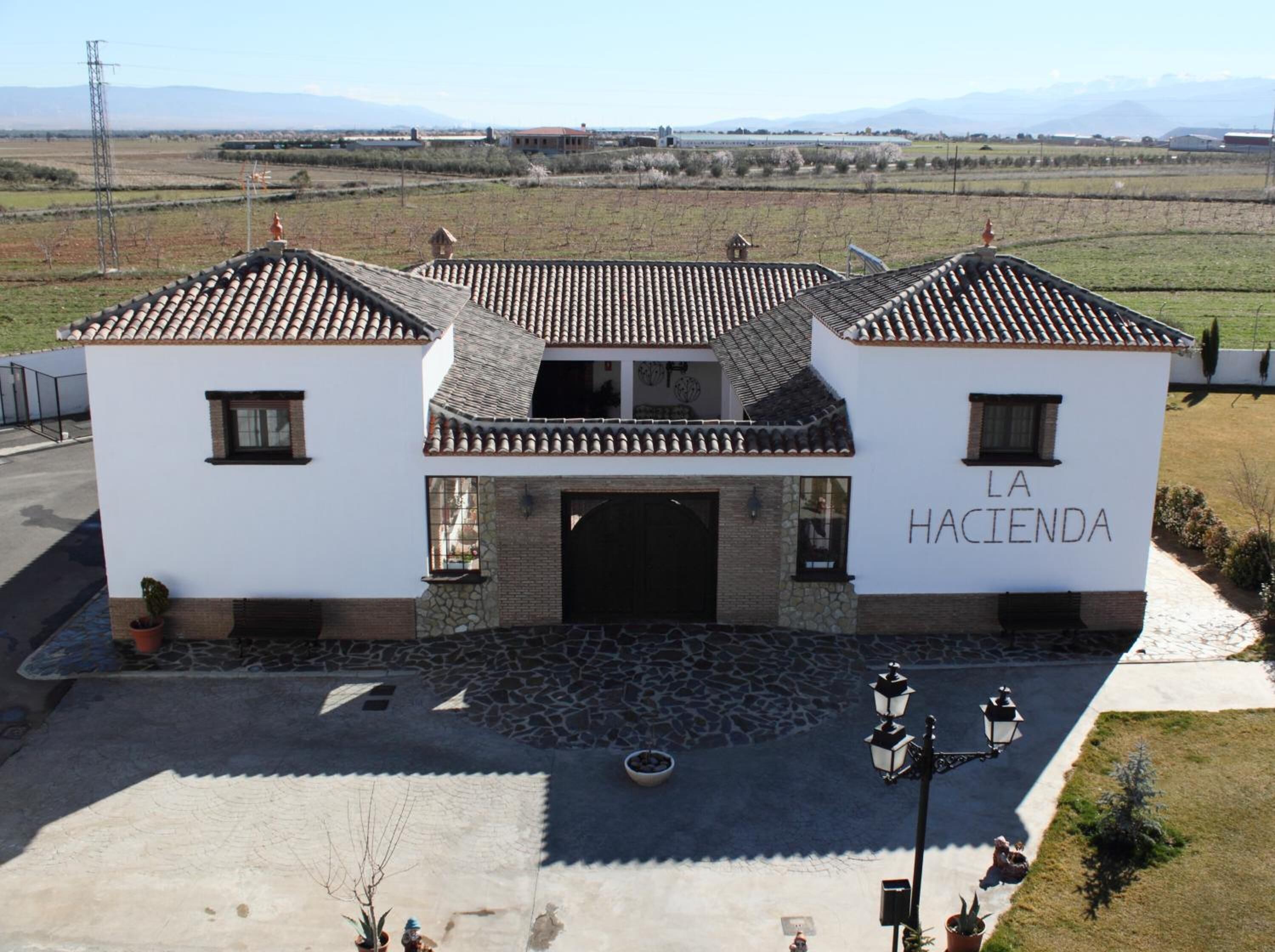 A two-story building with a tiled roof and a stone facade. The name "LA HACIENDA" is visible on the front wall.