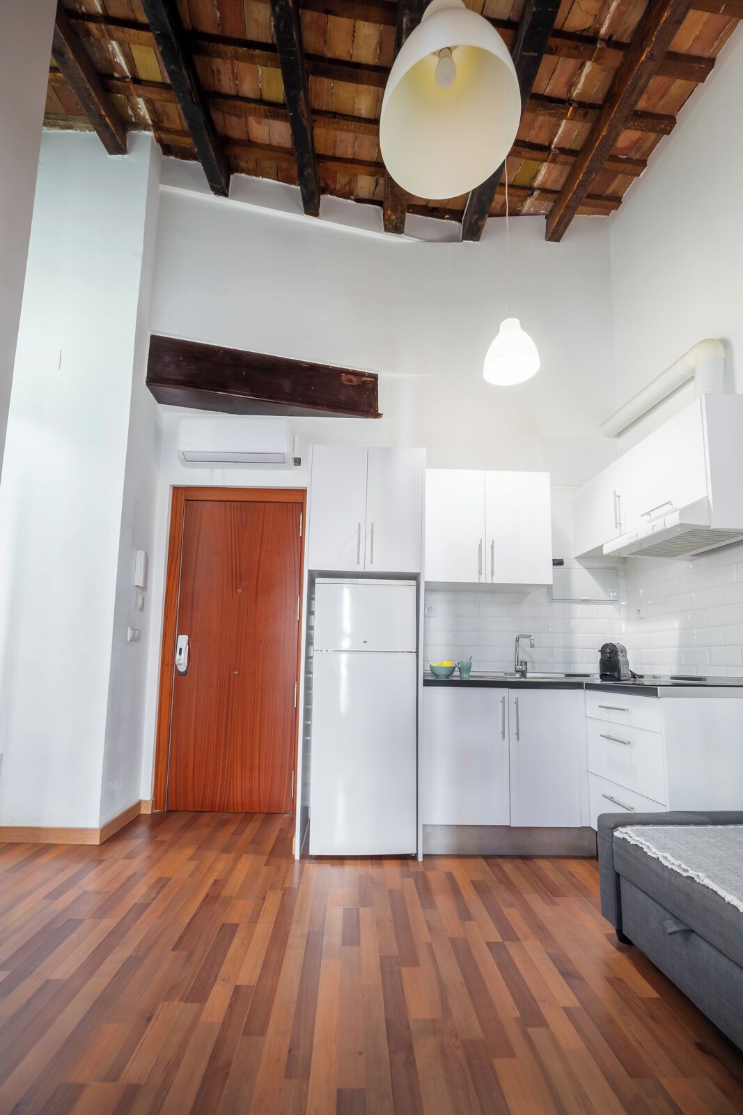 A modern kitchen with white cabinets, a built-in oven, and a wooden door.