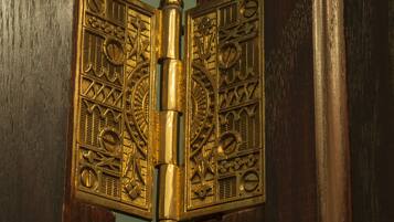 A brass door handle with intricate designs.