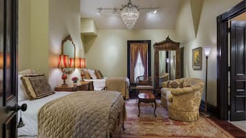 A hotel room with two beds, a chandelier, a large mirror, and a classic armchair.