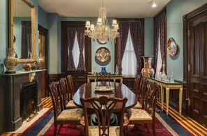 Ein elegantes Esszimmer mit einem großen Holztisch, verzierten Stühlen, einer Kristallleuchter und einem Kamin.