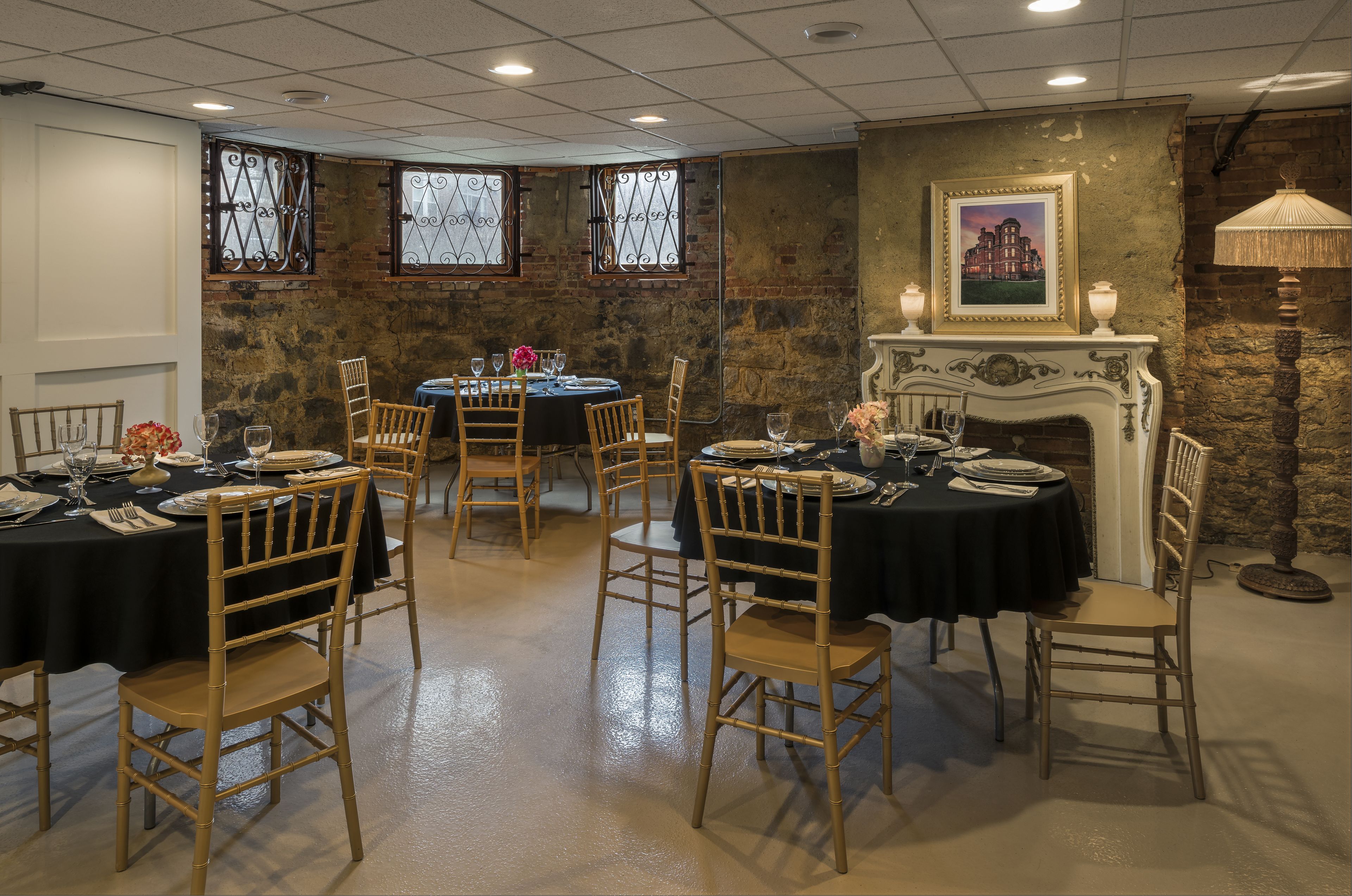 A dining area with round tables, wooden chairs, and a fireplace.