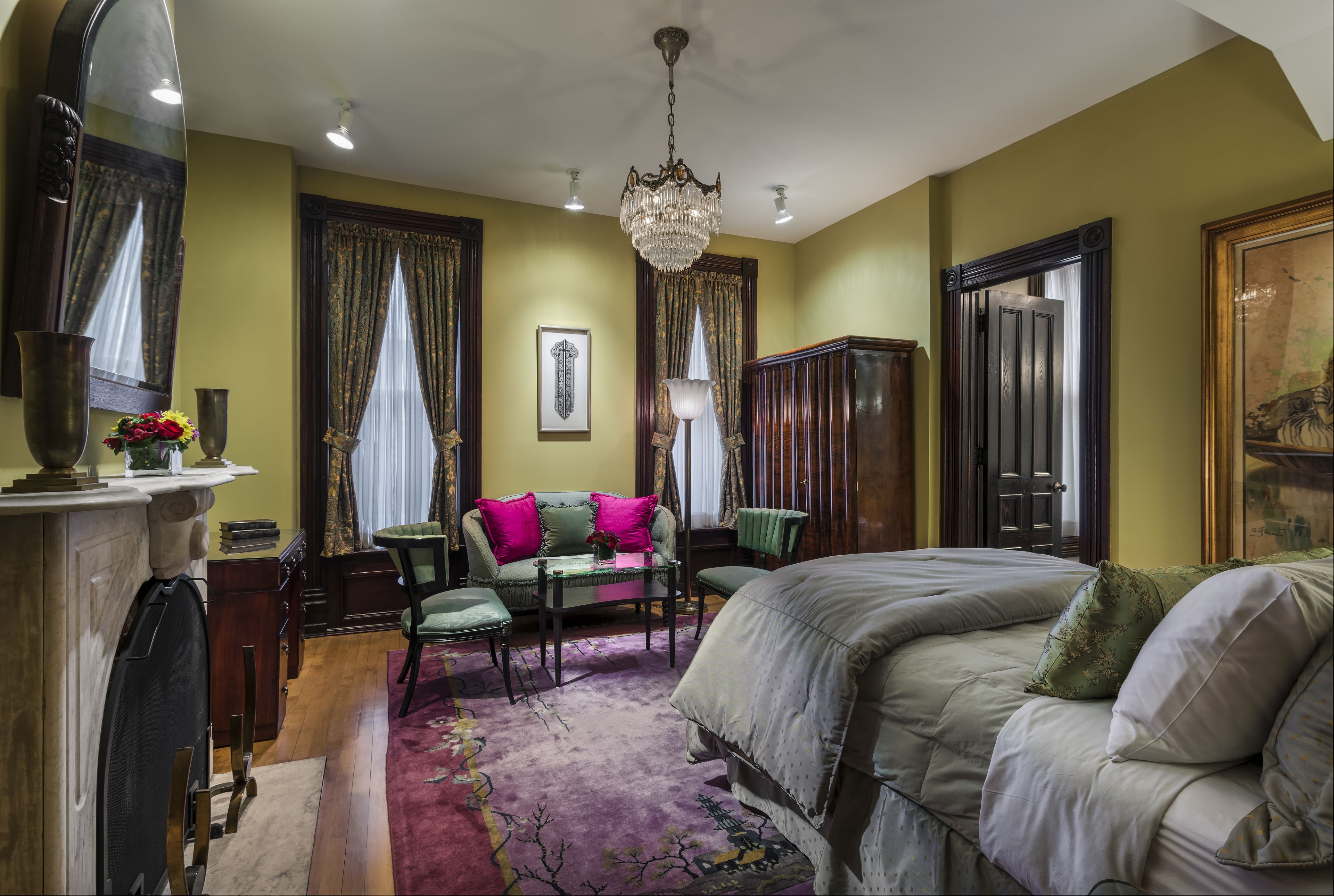 Una habitación con una cama, un sofá verde, una mesa y una araña.