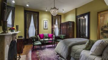 Una habitación con una cama, un sofá verde, una mesa y una araña.