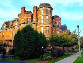 Un edificio de ladrillo grande y histórico con varias chimeneas y una prominente torre en esquina.