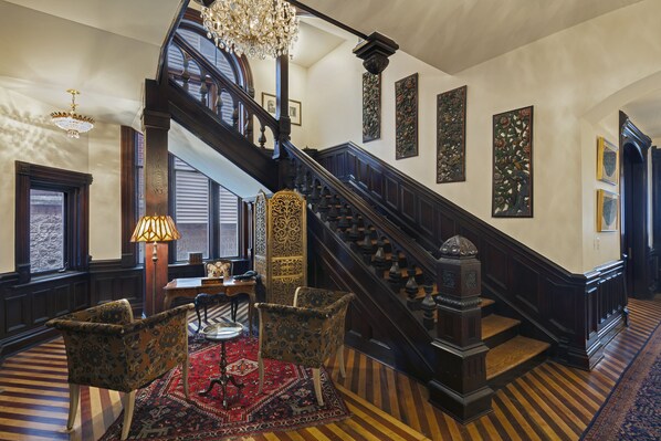 A grand staircase with ornate railings and a chandelier, leading to a second floor. - The Inn at 97 Winder (Detroit)