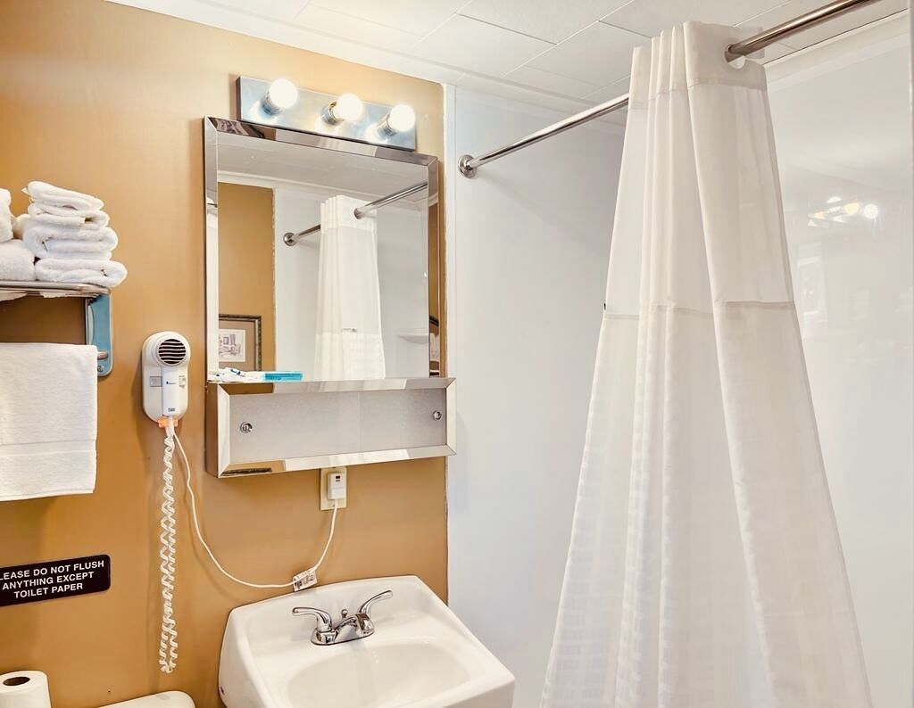 A bathroom with a sink, mirror, towel rack, and a shower curtain.